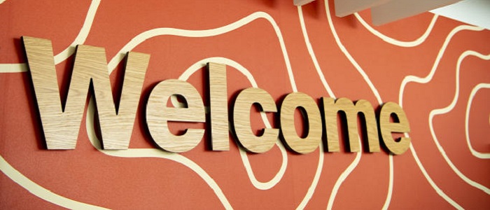 Big wooden letters saying 'Welcome' on an orange wall with squiggly white lines from inside the Clarice Pears Building at Glasgow University