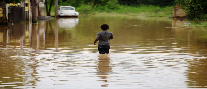 A small boy stands almost waist deep in floods