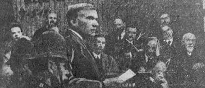 Black and white newspaper photo of John Maclean speaking from the dock in court with a paper in his hand Source: Wikimedia https://commons.wikimedia.org/wiki/File:Maclean_trial_1918.jpg