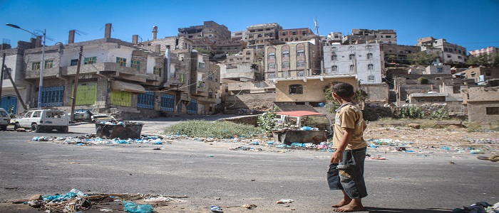A child looks at the ruins of houses around him in Yemen.