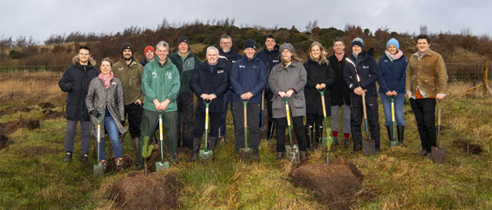 Image of staff from SBOHVM and UofG standing in a row holding spades in a field