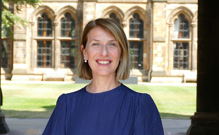 Prof Nuran Acur standing in the cloisters at the University of Glasgow