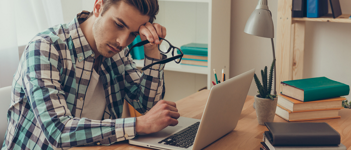 Man sits at his desk looking dejected