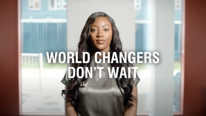 Screenshot from brand video showing an student behind the words 'World changers don't wait'.