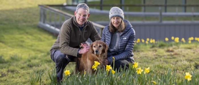 Man and Women smiling with dog among daffodils