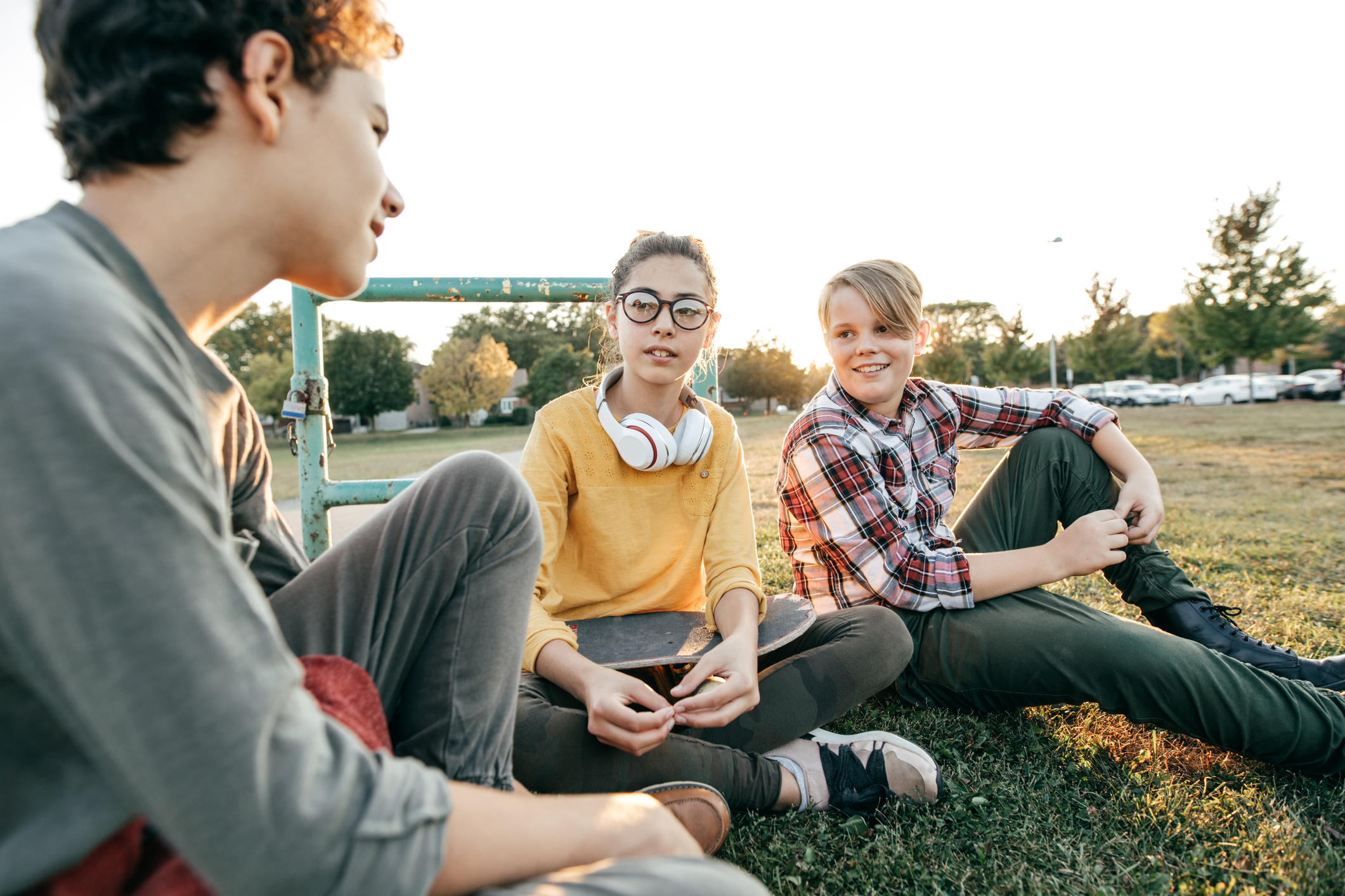 Three adolescents sitting on grass chatting