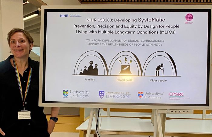 Photo of staff member Nic Dickson standing next to a prize winning poster at a conference