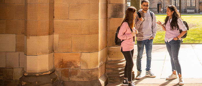 Three students standing in quadrangle chatting
