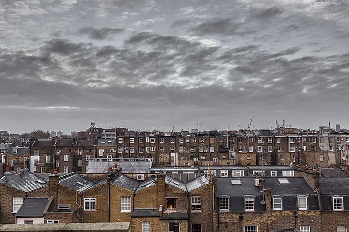 Rooftop view of old houses in London with grey sky and clouds. 700 pixels