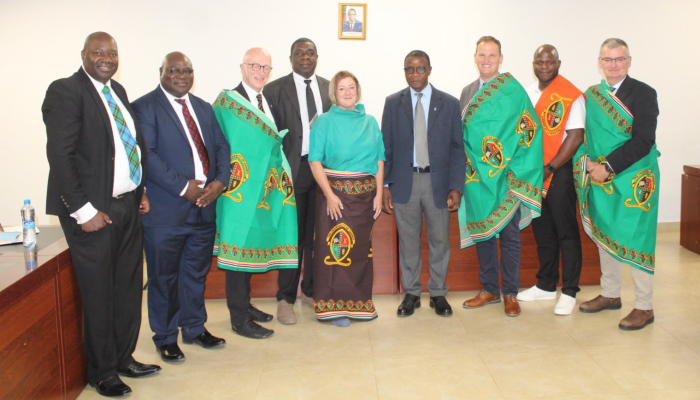 A University of Glasgow and Scottish Government Delegation stood in a line wearing traditional Zambian attire alongside University of Zambia
