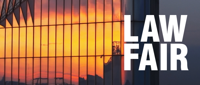 Sunset reflection on skyscraper facade with text: Law Fair