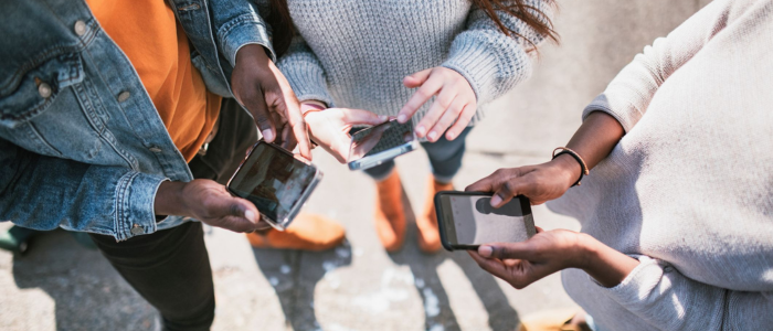 A group of adolescents holding mobile phones