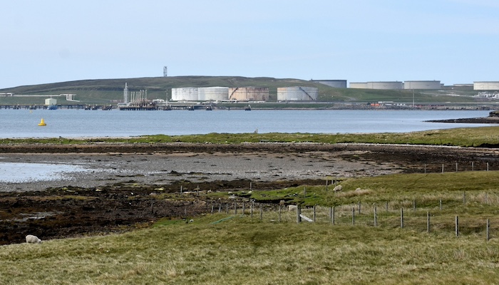 A view of Sullom Voe oil terminal with industrial building on the shore of an inlet of the sea. Photo credit: James Stringer, Flickr https://www.flickr.com/photos/jamesstringer/48068245541/