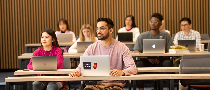 Audience members with laptops watching lecture