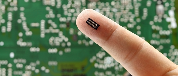 Finger with a small electronic piece on it with a green background