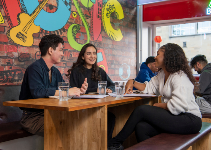 Students sitting at a table chatting in the QMU union
