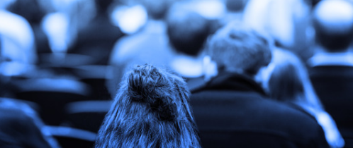 People sitting down listening to a speaker at a conference