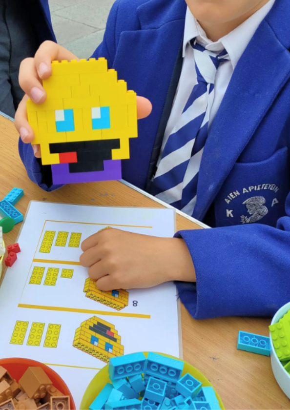A pupil holding a smiley face made out of Lego bricks