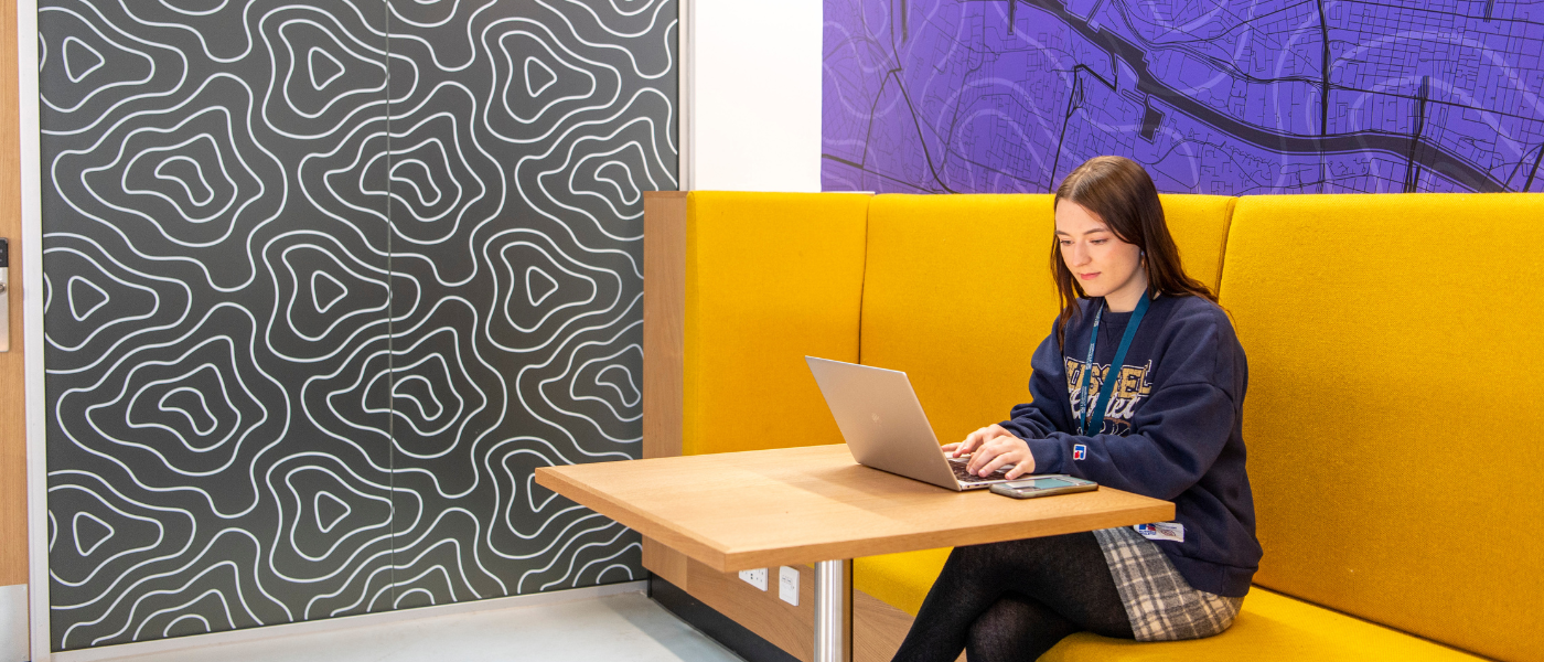 Staff member sitting at a table with a laptop in the clarice pears building