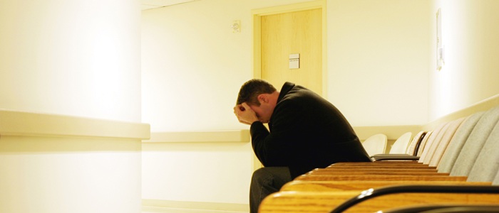 A man is sitting on a chair with his head in his hands