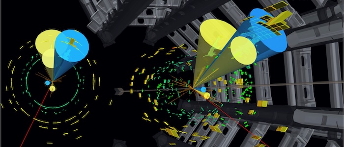 Candidate event for the top-antitop-quark pair process with a high-transverse-momentum, hadronically-decaying top quark. The hadronically-decaying top quark is reconstructed from the three particle jets in the upper half of the detector. One of the jets originates from a bottom quark (“b-tagged” in blue cone) and the other two jets (yellow cones) are consistent with being produced from a W-boson decay. The second top quark is reconstructed from the signals in the lower half of the detector: a second b-tagged jet (blue), an additional jet (yellow), a muon (red line) and the missing transverse momentum (not shown). Significant energy deposits are seen in the electromagnetic (green) and hadronic (yellow) calorimeters. Tracks of charged particles in the inner detector are visualised as orange lines.  Photograph: ATLAS Collaboration