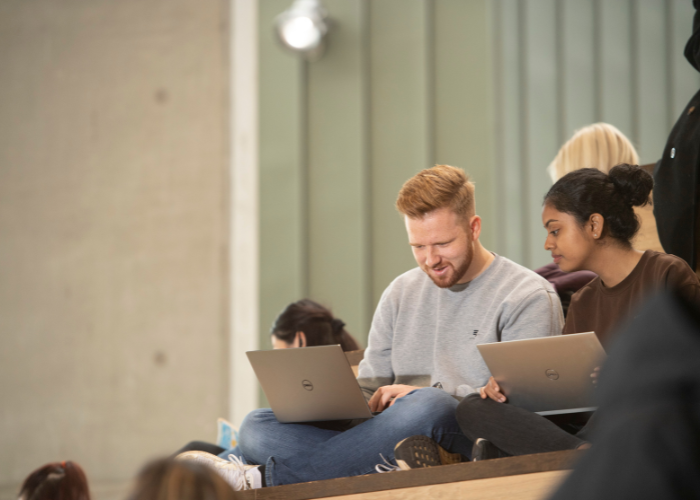 Students sitting in the JMS looking at laptops