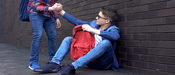 A teenager gives a helping hand to a peer.