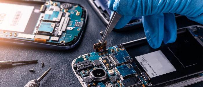 A gloved hand repairs a smart phone