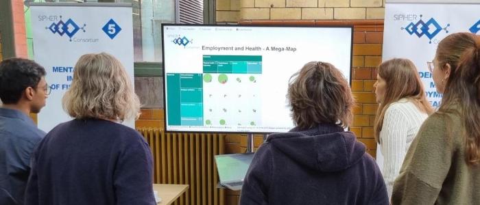 Group standing facing away to look at stand display at SIPHER Showcase event  