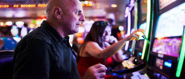 An elderly tourist uses a slot machine