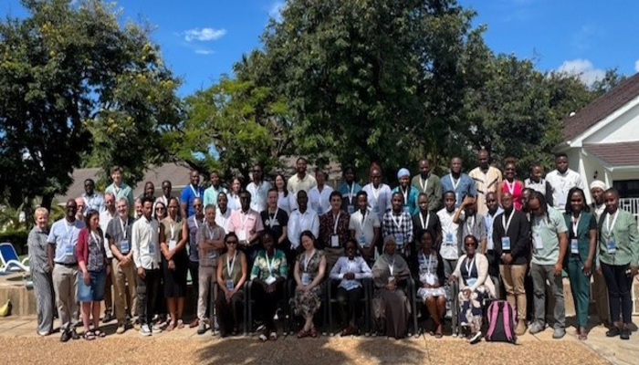 A gathering of academics, administrators, and participants from the 2025 AfriBOP stood together on a bright sunny day with blue skies against a backdrop of lush green trees