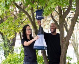 Dr Georgia Kirby and PhD student Meshach Lee with the mosquito trap next to a tree.