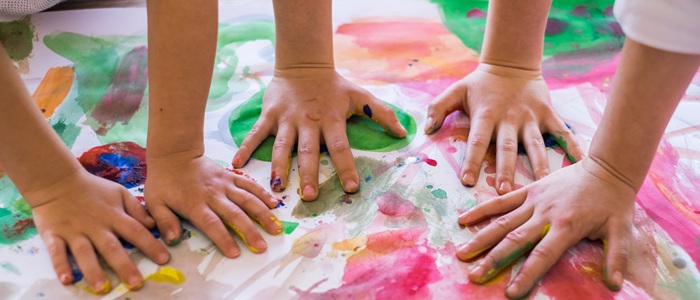 Children's handprints with bright pink and green paint on white paper