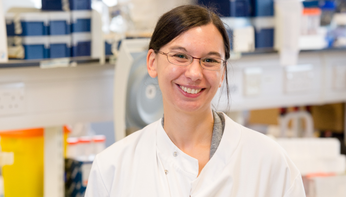 A head and shoulders shot of a smiling Dr Megan Macleod in the lab wearing white lab coat