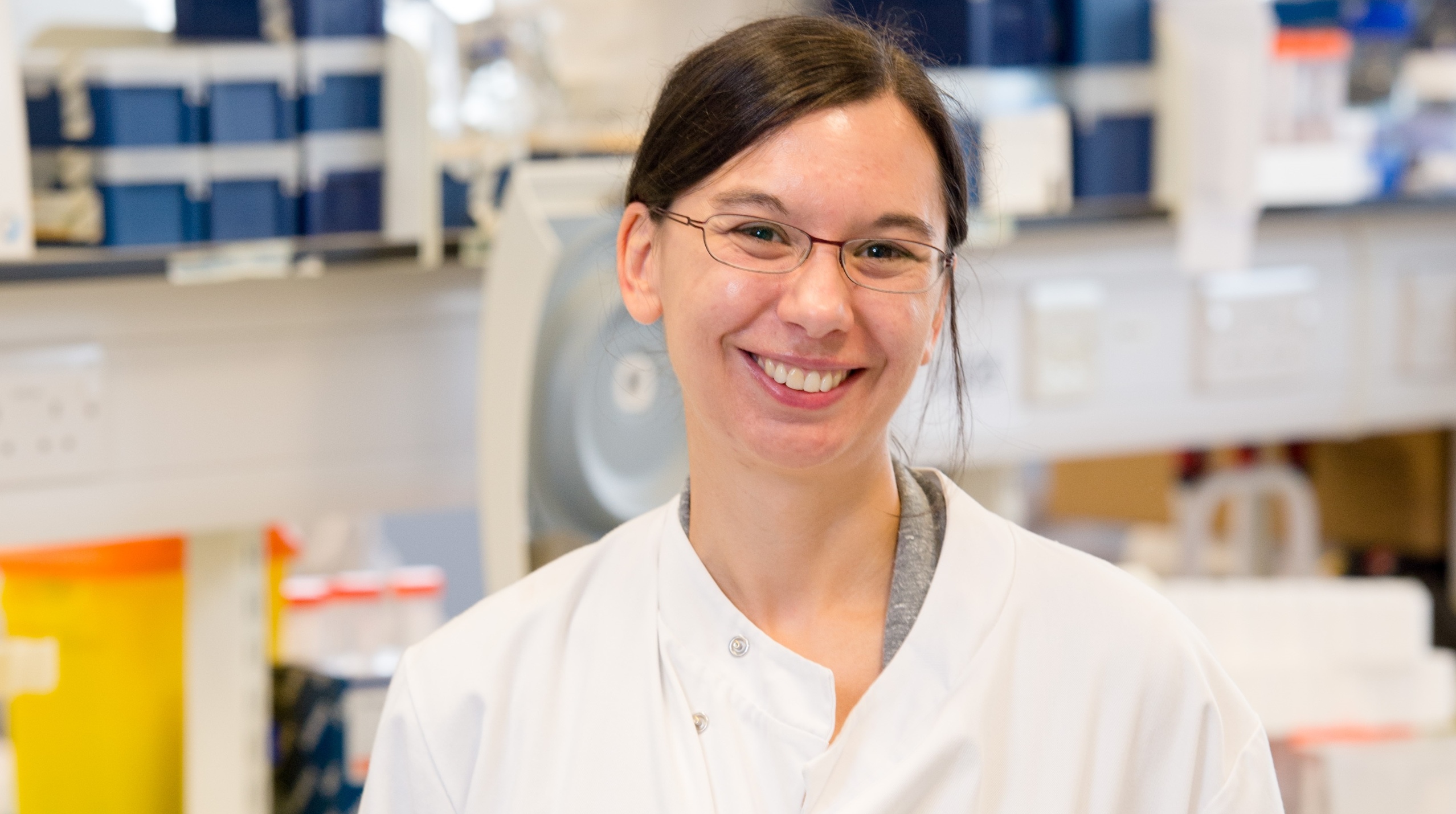 A head and shoulders shot of a smiling Dr Megan Macleod in the lab wearing white lab coat