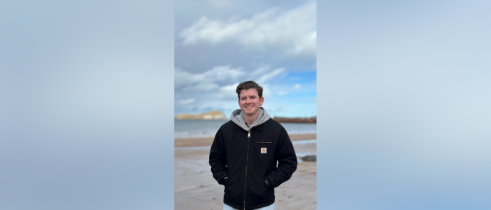 A man standing on a beach smiling to the camera