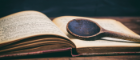 Wooden spoon lying on top of an aged cookbook with a dark background