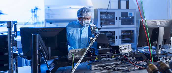 Researcher wearing hairnet and lab coat conducting physics research