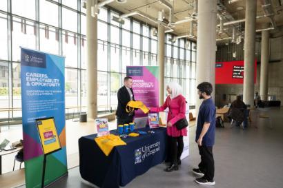 An employer talking to two students at a stand at the The Avenue space in James McCune Smith Learning Hub