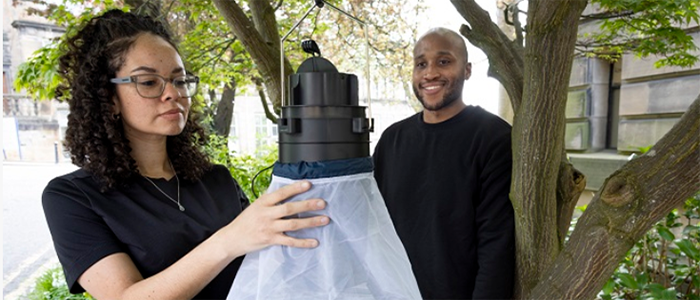 Image of Dr Georgia Kircy and PhD student Mashaca Lee hanging a mosquito trap in a tree