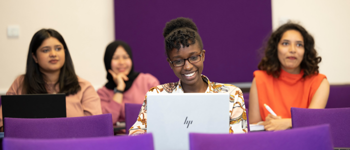 A Student sitting in a lecture theatre looking at their laptop