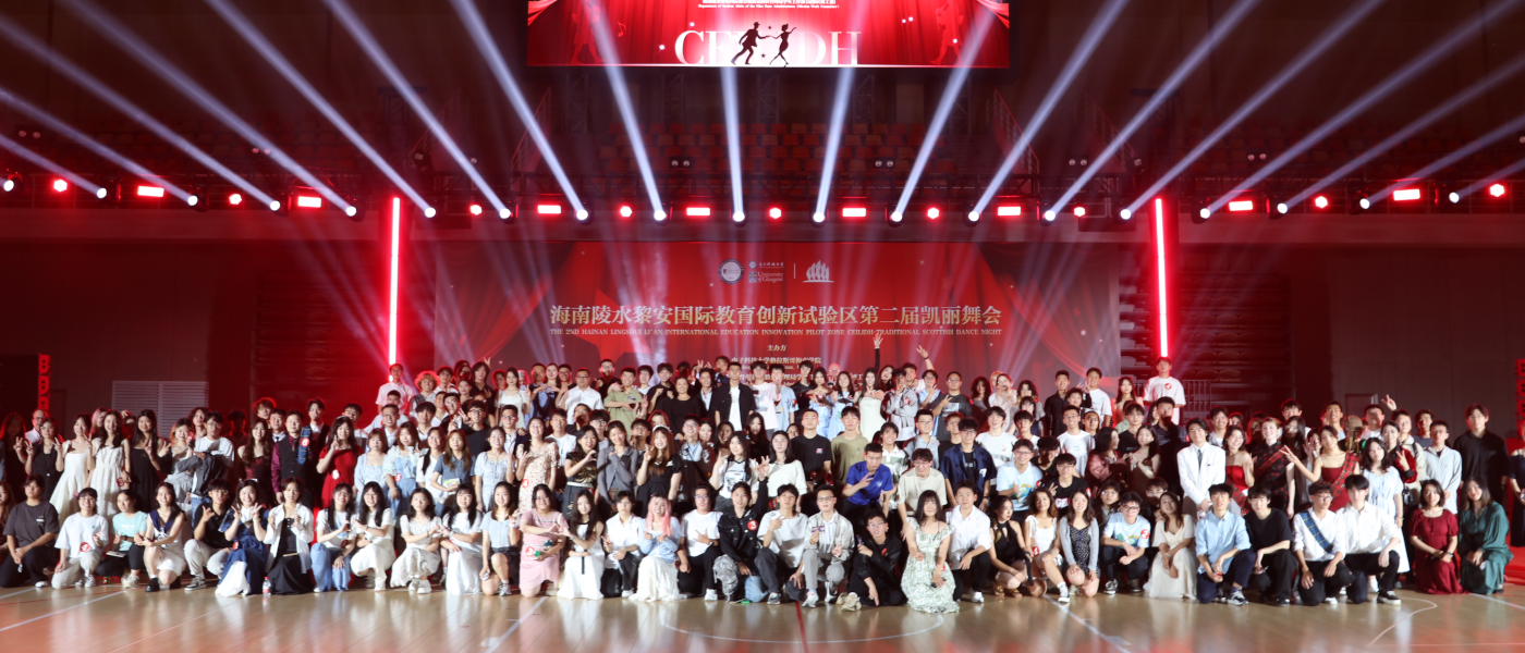 Students and staff who attended the Hainan 2025 Ceilidh pose for a group photo against a red backdrop in an auditorium