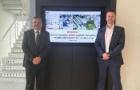 Two men posing in front of a TV screen