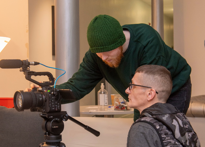 Two students looking at the screen of a camera on a tripod