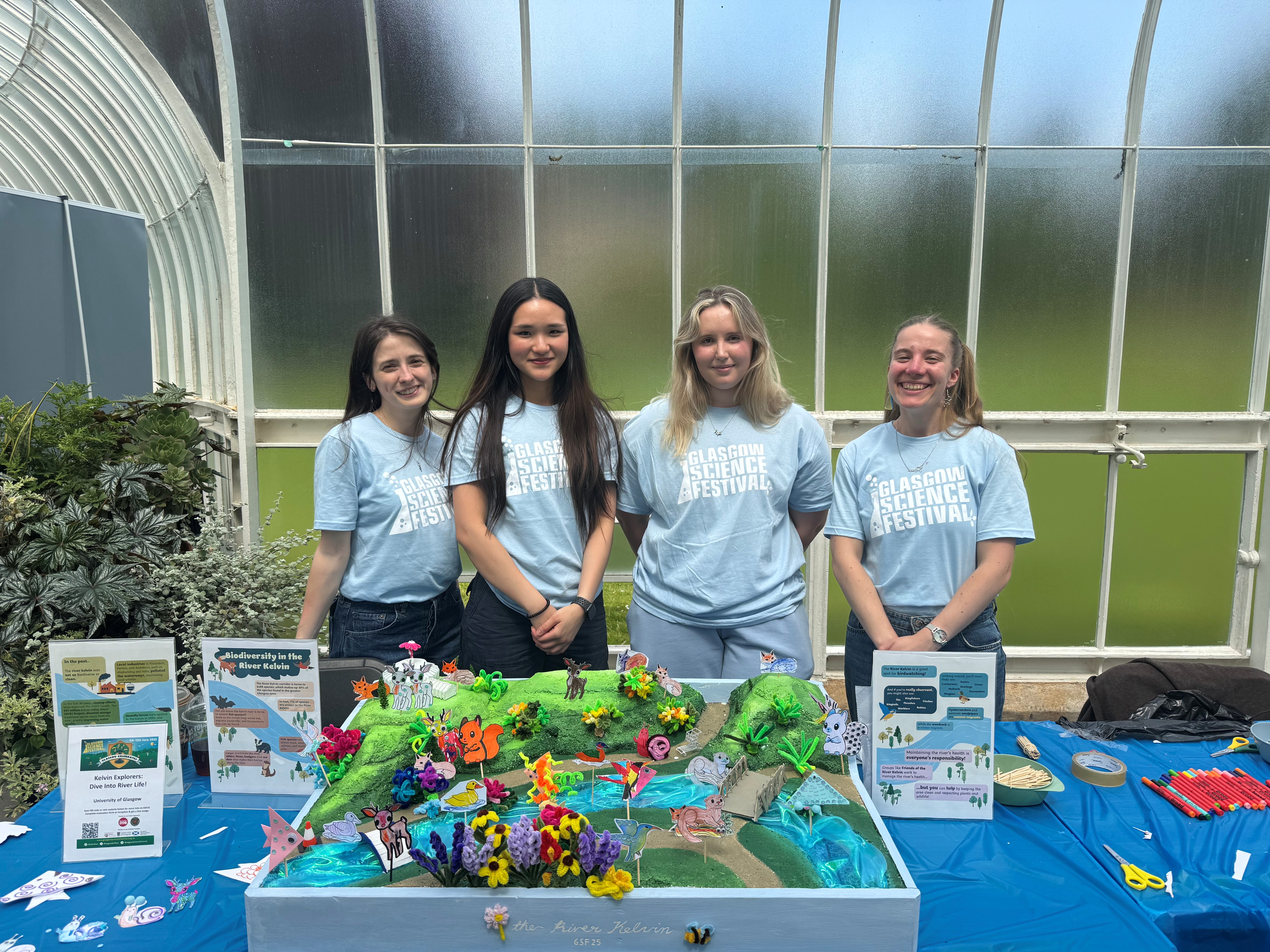 Four people wearing GSF Tshirts standing behind a table with a colourful 3D mural of the river kelvin sitting on a table