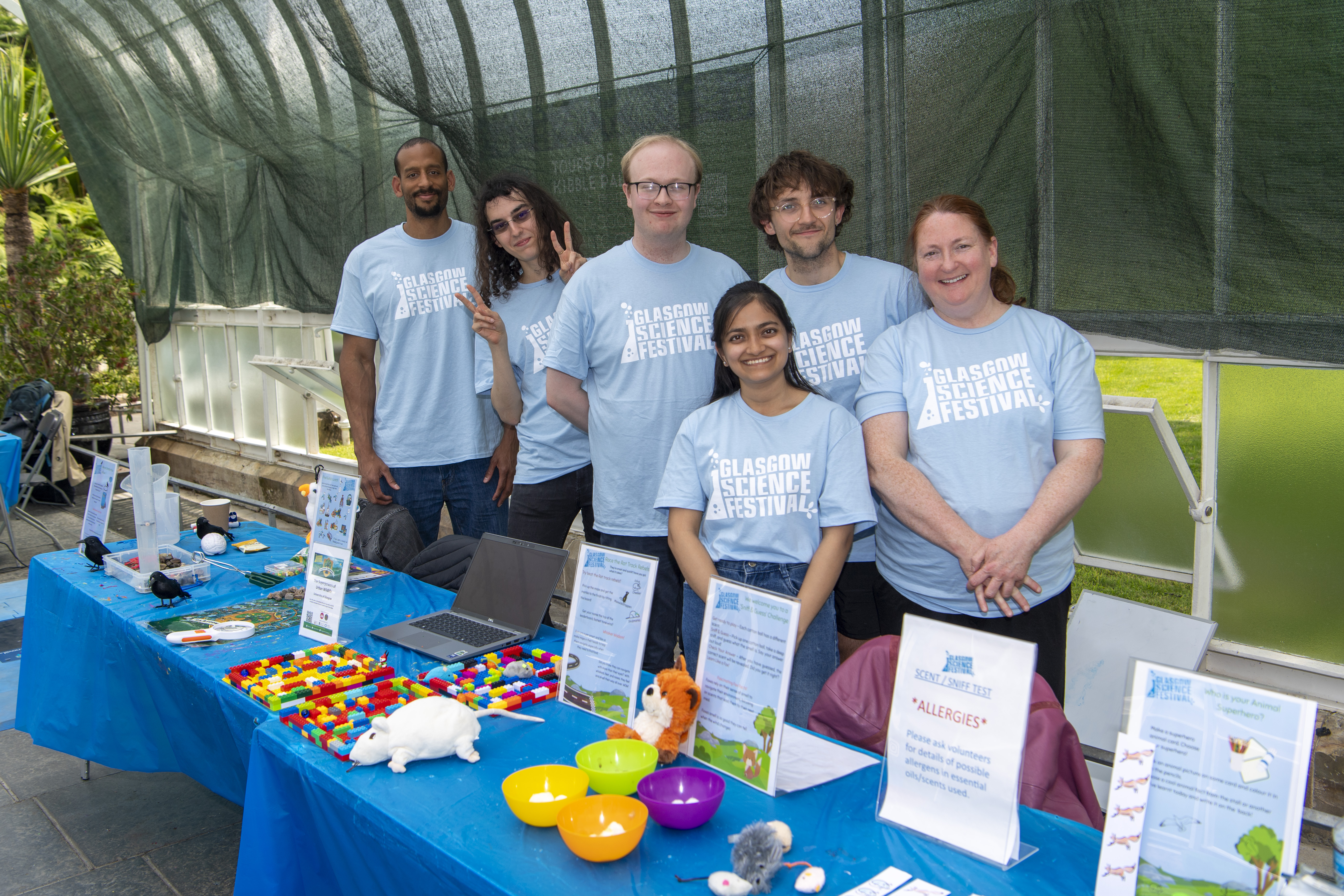 Six people wearing GSF Tshirts standing behind a table with colourful activities