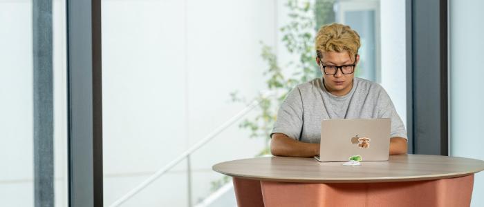 Student sitting with laptop in Adam Smith Business School Postgraduate Hub
