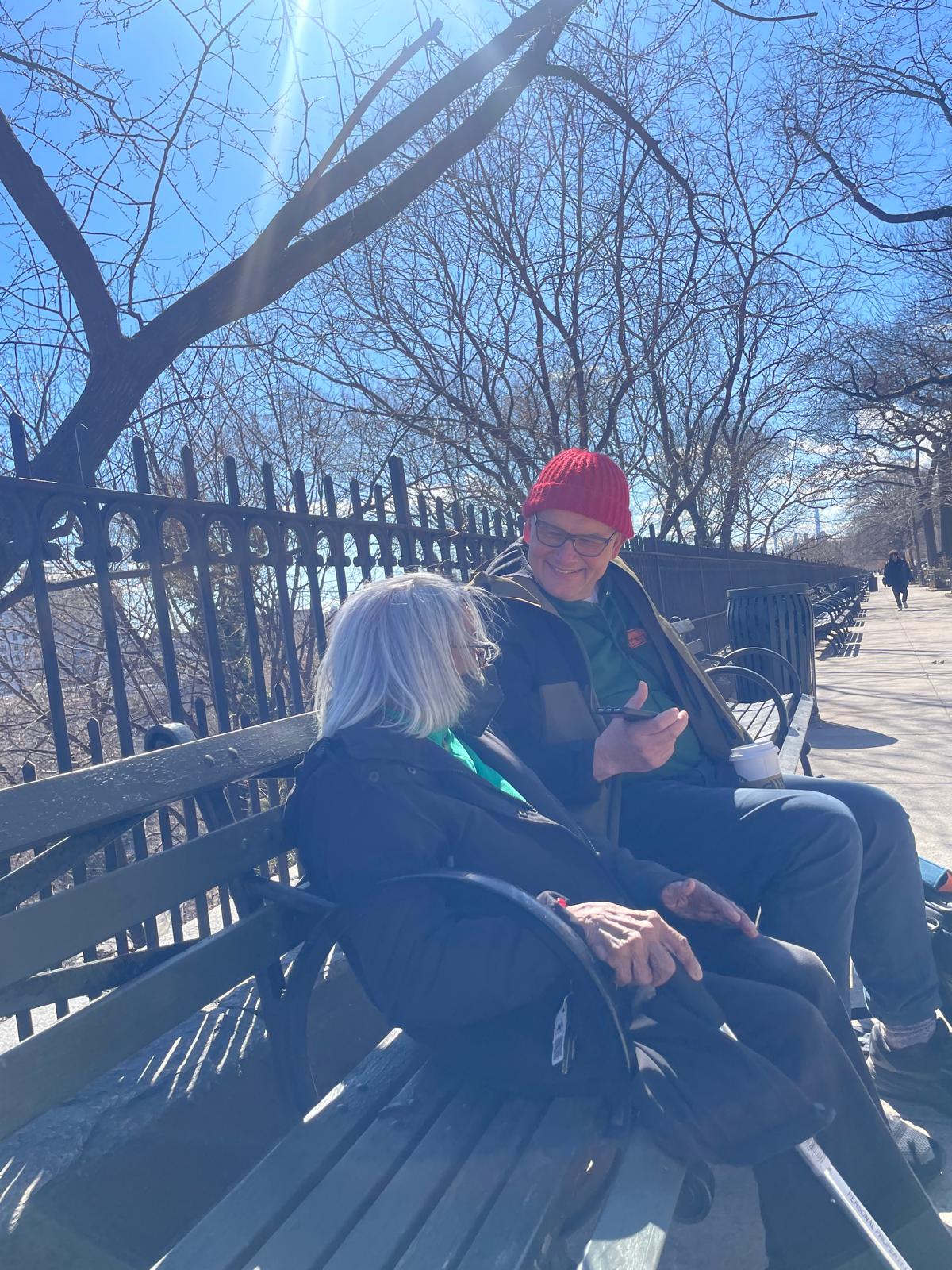 Man and woman sitting on a bench in the winter sun talking