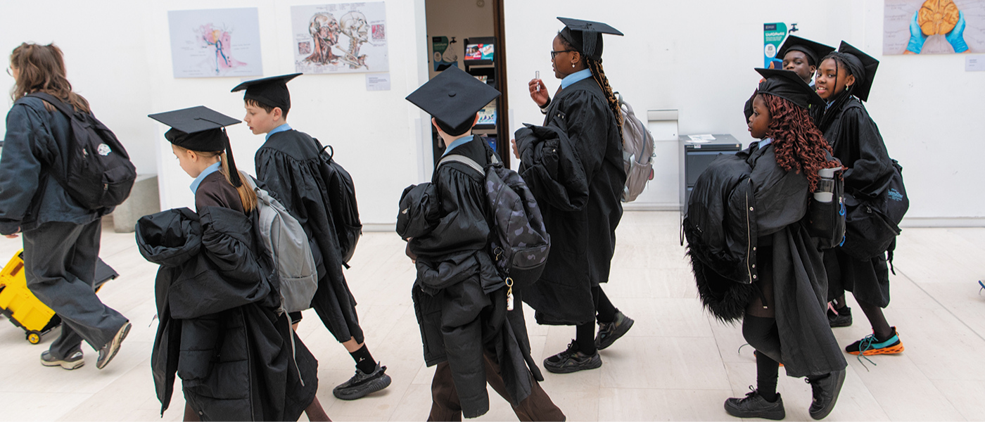 Primary school children walking in graduation robes