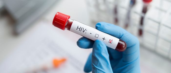 Gloved hand holding a blood sample tube labelled 